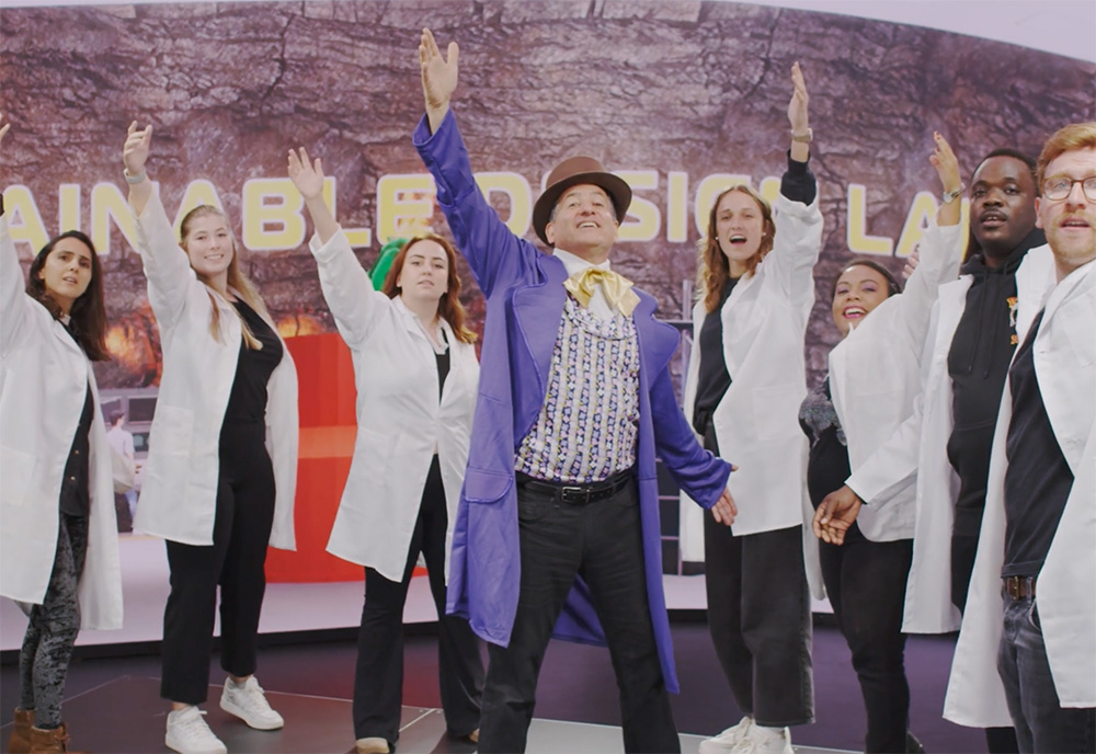 TH Culhane stands with students dressed in white coats as they finish a music number for one of his course videos