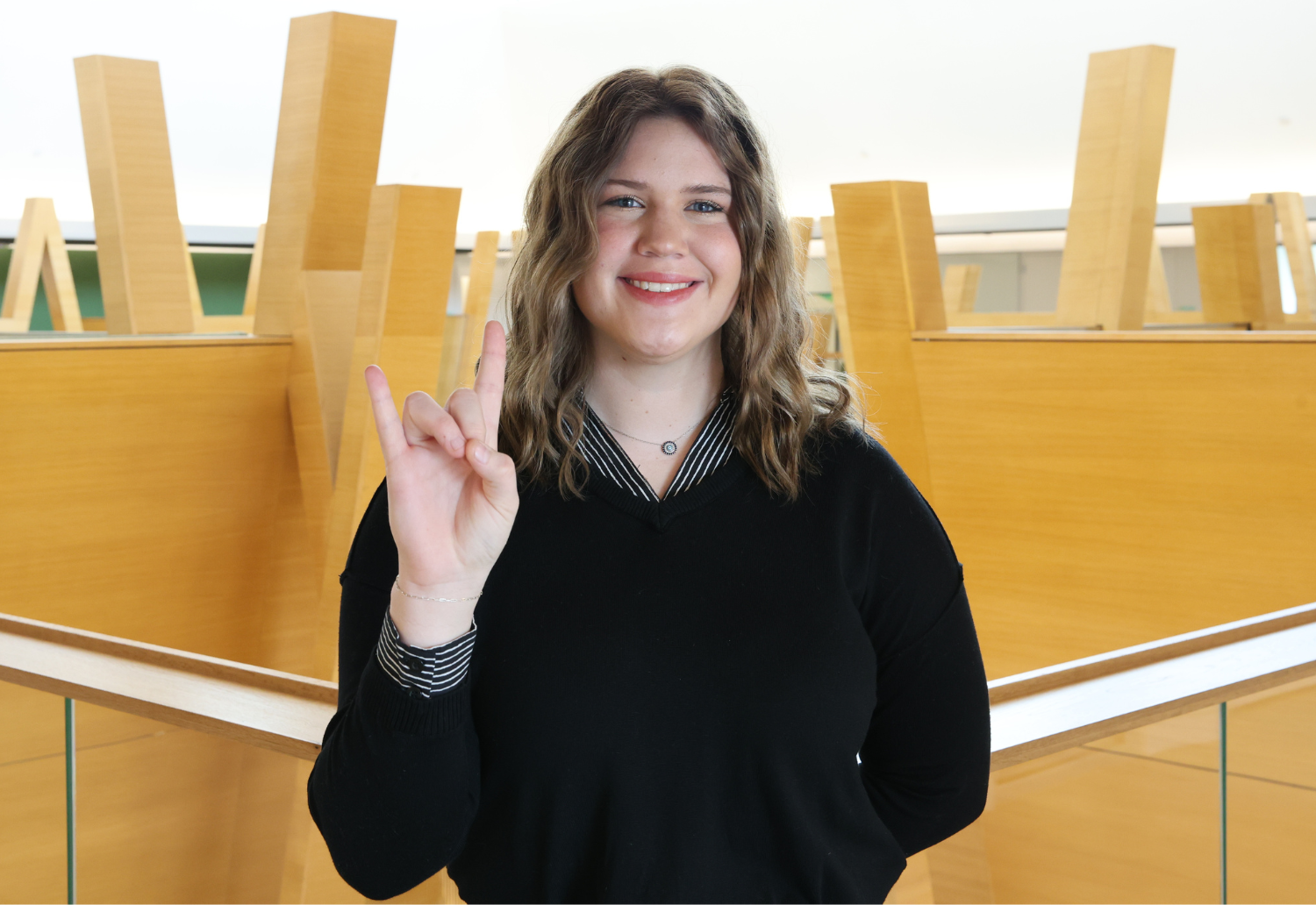 Ashley Parow stands in Honors College holding up Go Bulls hand sign