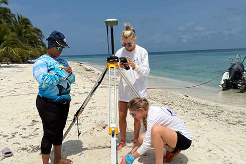 USF graduate students Libby Royer and Lara Novalvos Hernandes (right) set up equipment to study beach erosion on a reef island near Placencia, Belize.