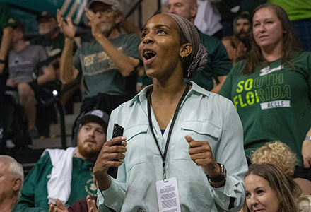 a woman reacts to a great play with a crowd behind her