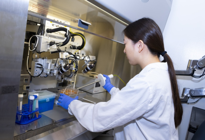 Student holding pipetting tools over petri dish in a lab
