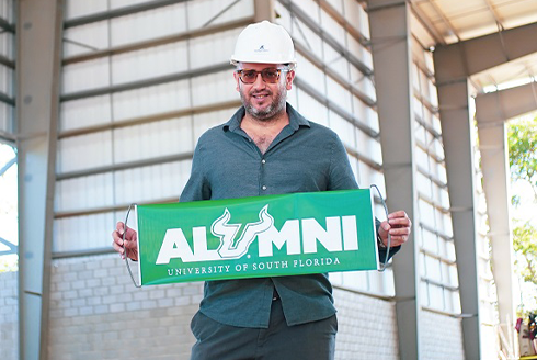 Rene Jacir posing with a aoa体育 green banner that says